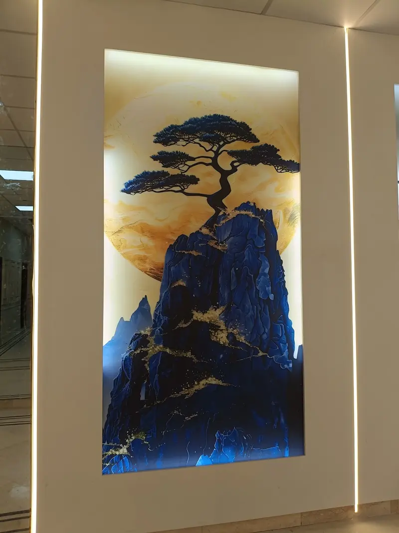 Backlit panel of a bonsai tree against blue mountains, lit from behind