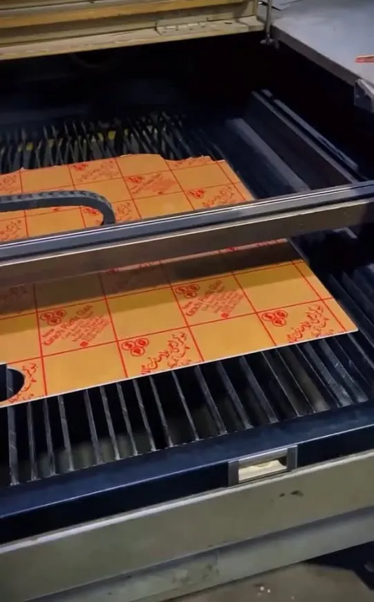 Laser cutter cutting a sheet of orange acrylic